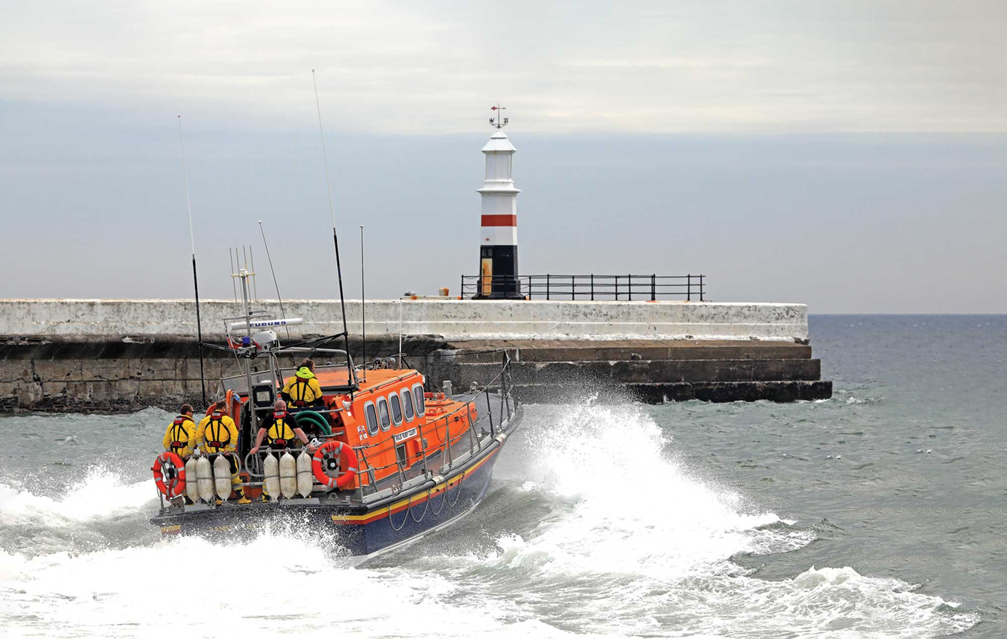 A fully-crewed RNLI lifeboat launching off the coast of Ramsey, Isle of Man